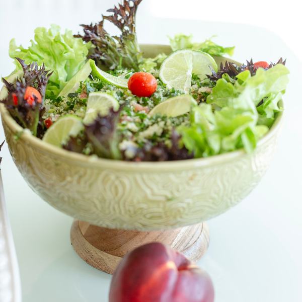 Green salad with tabbouleh, lime and cherry tomatoes in a ceramic bowl