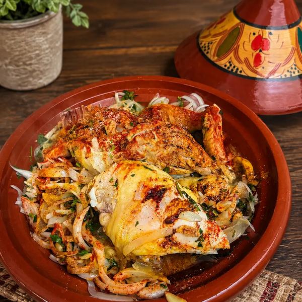 Moroccan chicken tagine with onions and spices in a clay dish