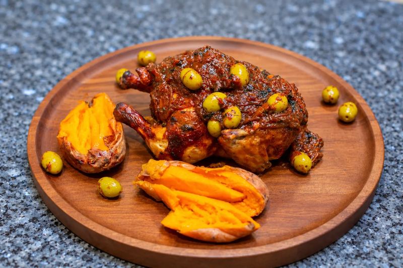 Moroccan-spiced roasted chicken with green olives and sweet potato on a wooden board