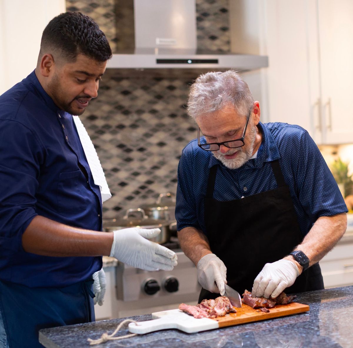 Chef Youssef guiding a guest as they carve roasted meat together